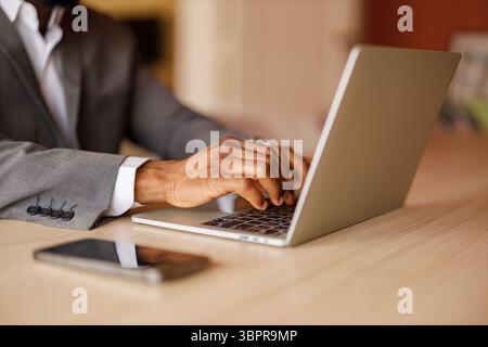 Cropped hands of male entrepreneur typing e-mail on laptop keyboard at desk in corporate office Stock Photo