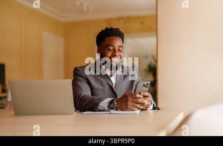 Portrait of smiling businessman using online applications over smart phone while working in office Stock Photo
