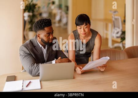 Professional managers analyzing reports using documents and laptop focused on business performance in office Stock Photo