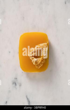 Turmeric soap bar on marble white background. Organic skincare product and bath accessories. View from above. Vertical. Stock Photo