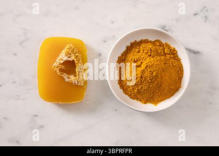 Turmeric soap bar and powder turmeric root on marble white background. Organic skincare product perfect for wellness, beauty, and organic body care co Stock Photo