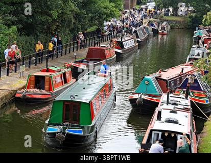 A canal holiday hire boat from the Andersen Boats company passes the crowds of folk on the bank of the Bridgewater canal for Lymm transport day Stock Photo