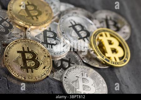 An arrangement of golden and silver Bitcoin coins placed on a textured stone surface, symbolizing cryptocurrency and digital currency concepts. Stock Photo