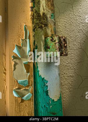 Detail of door hinge with colorful peeling paint and dramatic light, Indiana USA Stock Photo