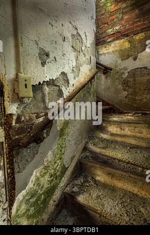 Peeling paint and chipped plaster inside dilapidated stairs, abandoned building, Rockville Indiana USA Stock Photo