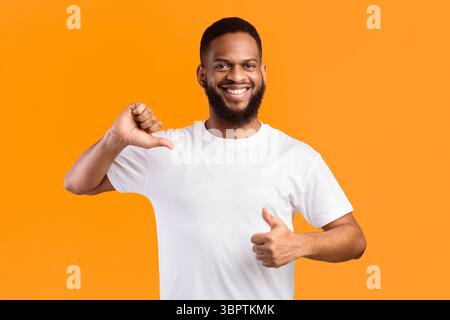Cheerful Black Guy Pointing Thumbs At Himself On Yellow Background Stock Photo