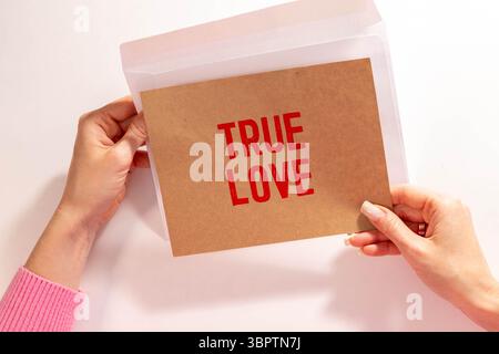 The text True Love appearing behind torn brown paper Stock Photo