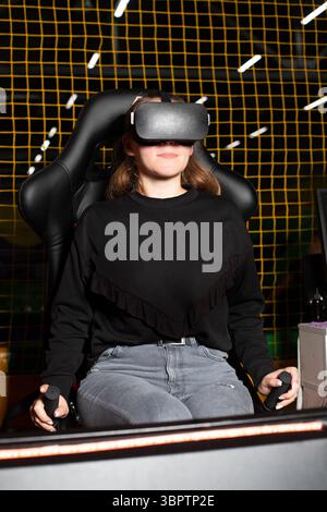 A girl playing a video game with glasses looks at reality. Virtual games with VR headsets. Stock Photo