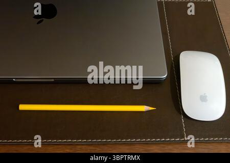 Sharp yellow pencil on desk with Mac laptop and mouse Stock Photo