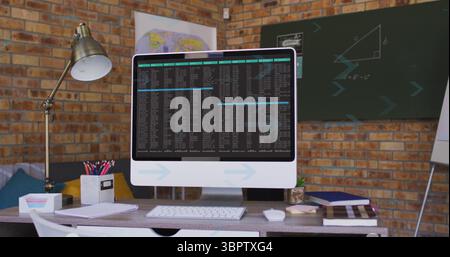 Flat screen computer monitor displaying code on desk in study room, with lamp, keyboard, mouse, map Stock Photo