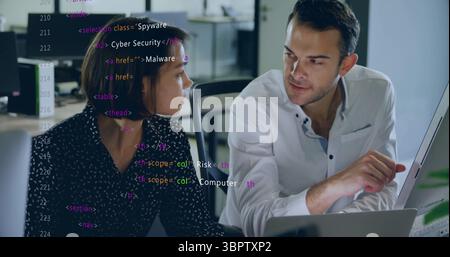 Coworkers reviewing HTML cybersecurity code in open-plan office, with computer monitor Stock Photo