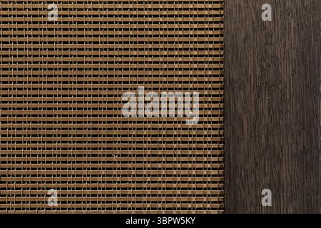 Macro detail of a woven bronze metal mesh cabinet door insert next to dark oak wood. A modern and sophisticated interior design texture and background Stock Photo