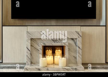 A modern marble fireplace filled with glowing candles in glass holders, creating a cozy and elegant ambiance. A stylish alternative to a traditional f Stock Photo