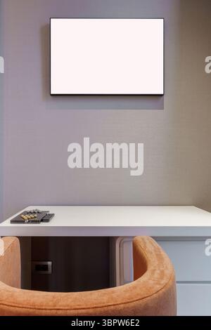 Minimalist home office or vanity corner. Features a white desk, an orange chair, and a blank horizontal frame for mockup. Modern interior background. Stock Photo