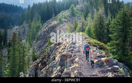 A single senior female and her black lab hike along a exposed ridge on the Grand Mesa in western Colorado. Stock Photo