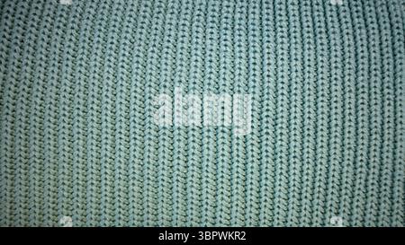 The background is filled with the texture of knitted fabric of mint green color. Macro photo. Vertical stripes. Pattern. Background. Turquoise. Stock Photo