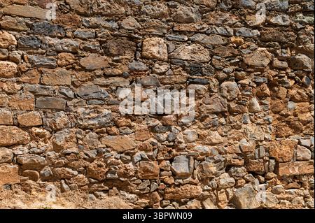 Detailed view of a textured stone wall highlighting unique shapes and earthy tones. Stock Photo