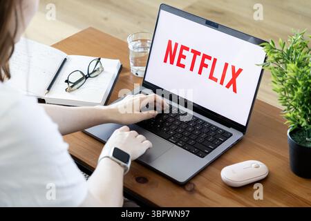 Poznan, Poland - June 15, 2025: Netflix platform prominently displaying its logo on a modern laptop, with a person actively engaging for personal ente Stock Photo