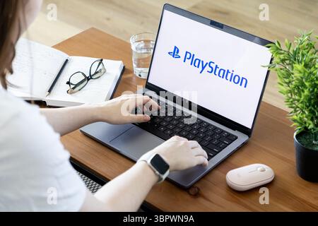 Poznan, Poland - June 15, 2025: PlayStation logo prominently displayed on laptop screen, with a person typing, representing modern digital entertainme Stock Photo
