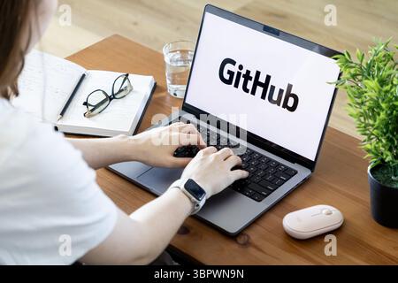 Poznan, Poland - June 15, 2025: Hands typing on a laptop showing GitHub, an essential platform for collaborative software development, version control Stock Photo