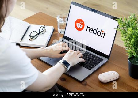 Poznan, Poland - June 15, 2025: Reddit application logo visible on laptop screen, a person typing, illustrating active engagement with the vast online Stock Photo