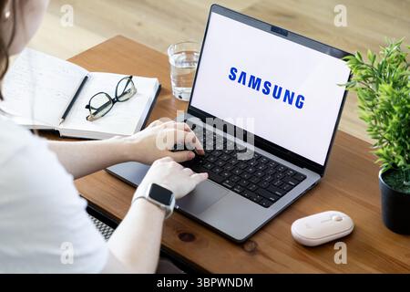 Poznan, Poland - June 15, 2025: SAMSUNG brand logo visible on a laptop screen from a top-down perspective, with hands typing, showcasing digital engag Stock Photo