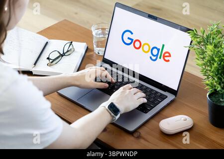 Poznan, Poland - June 15, 2025: Google's search interface on a laptop, with hands typing for information retrieval, illustrating web browsing and data Stock Photo