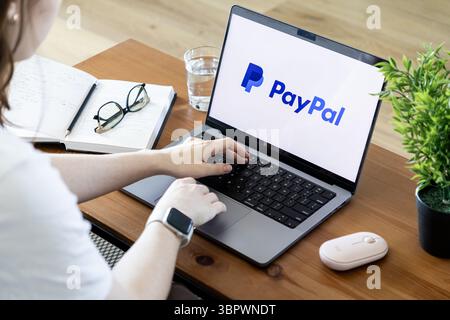 Poznan, Poland - June 15, 2025: User interacting with a laptop featuring the PayPal application, demonstrating secure online financial transactions fo Stock Photo