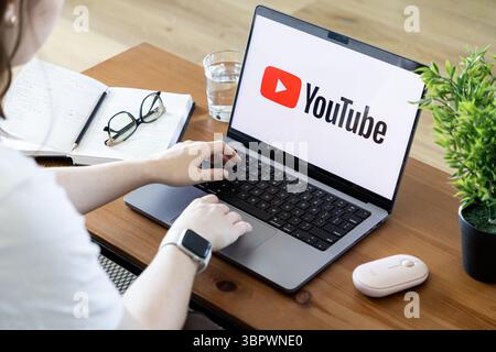 Poznan, Poland - June 15, 2025: YouTube application displayed on a laptop screen, as a person types, streaming popular online video content and digita Stock Photo