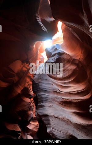 A beam of sunlight breaks through the narrow walls of Antelope Canyon revealing red and orange sandstone waves sculpted by time in Page Arizona desert Stock Photo