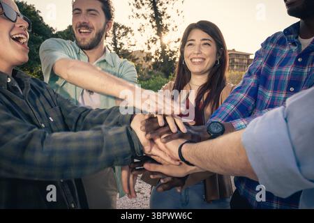 Close-up of a diverse multiethnic group of friends stacking their hands in the center, symbolizing teamwork, unity, support, and a successful collabor Stock Photo
