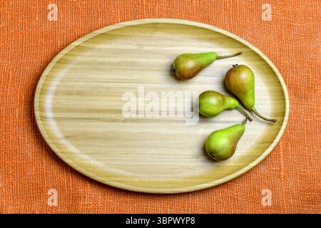 Small green juicy pears are lying on wooden platter. Healthy food, diet. Top view. Copy space. Selective focus. Stock Photo