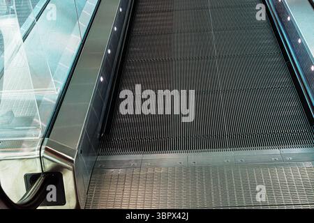 Closeup of metallic escalator surface at the airport. Detailed  shot of the metallic ridges on an escalator step, showing modern industrial design and Stock Photo