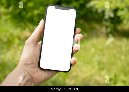 Close up of womans hands holding smartphone in outdoor green setting. Check apps, focused on device, chatting, performance data. Voice assistant. Fitn Stock Photo