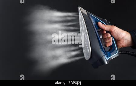 Hand operating the steam system of an iron and view of steam jets on dark isolated background Stock Photo