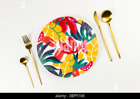 Top view of colorful plate, gold cutlery on white background. Exotic plant plate, summer picnic. Flat lay, copy space. Stock Photo