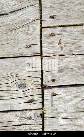 Detailed close-up of a rustic wooden wall with weathered, gray-toned slats arranged in an offset pattern Stock Photo