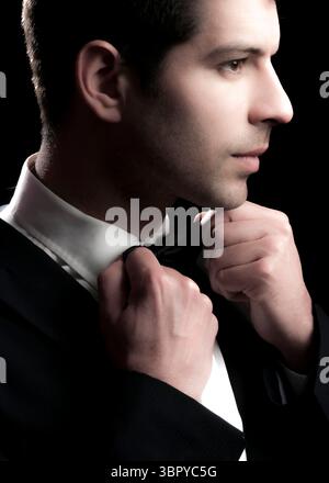 A man in a suit is adjusting his bow tie. Stock Photo