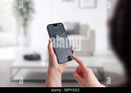 Woman interacting with smart home interface on mobile phone in modern interior environment Stock Photo