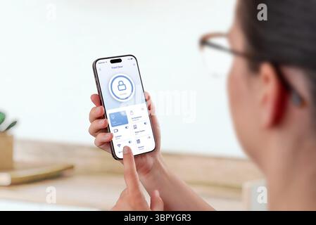 Woman using smartphone smart home app with door lock and device management functions Stock Photo