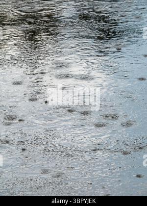 Heavy rain on the a street, close up image. with puddles. Stock Photo