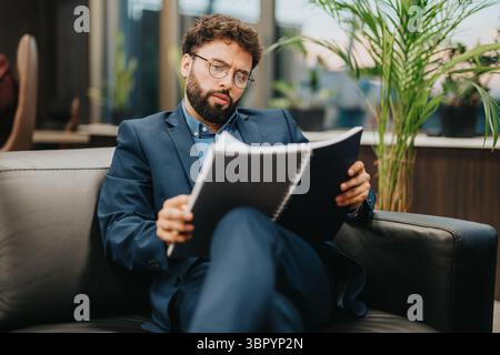 Business professional reviewing documents while seated in a modern office setting Stock Photo