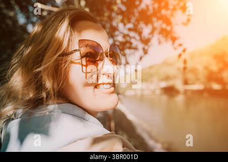 Woman Sunglasses River - Close-up of a woman wearing sunglasses while looking towards a river in the background. Stock Photo