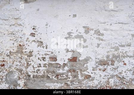weathered brick wall with crumbling white plaster for background use Stock Photo