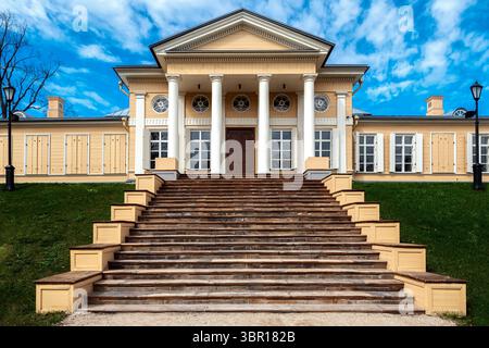 Wooden house with white columns and a wide staircase with stone steps leading to it. Stock Photo
