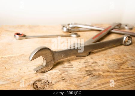 collection of metal wrenches and tools, with an 18mm wrench in foreground focus, arranged on a rustic wooden surface. Stock Photo
