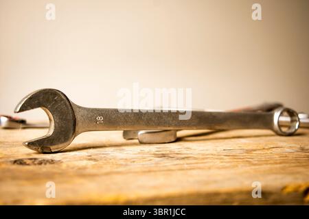 An 18mm steel combination wrench prominently displayed on a textured wooden surface, embodying themes of repair, DIY, and craftsmanship. Stock Photo