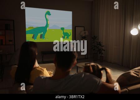 Family watching cartoon using video projector on sofa at night Stock Photo