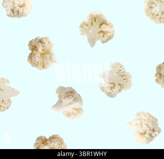 Fresh cauliflower florets falling on light blue background Stock Photo