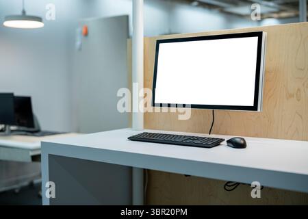 Office cubical with computer display and keyboard with mouse Stock Photo
